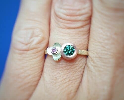 Diamantring boleet en in bloei met saffier. Hier wordt de kleurrijke ring om de vinger geshowt.