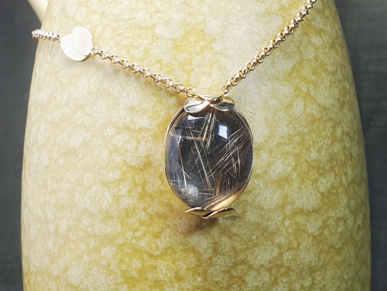Golden necklace with a rutilated quartz pendant with leaves. Design by Oogst jewellery in Amsterdam