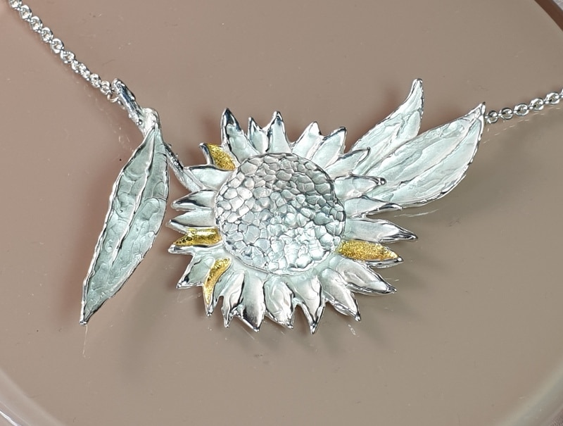 Assieraad. Zilveren Zonnebloem collier met bladgoud details. Maatwerk van Oogst Goudsmeden in Amsterdam