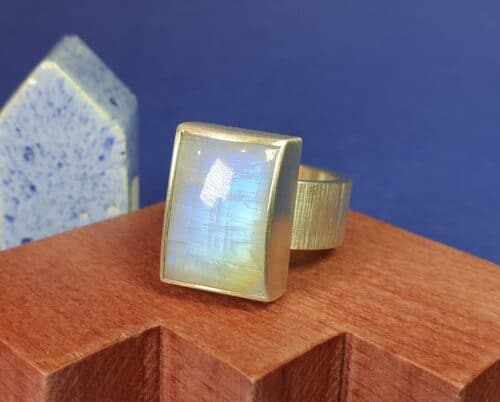 Gedenksieraad. Zilveren ring met maansteen, waaronder wat as wordt bewaard. Maatwerk uit het Oogst atelier in Amsterdam