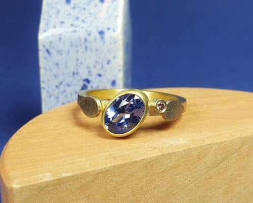 Ring met eigen ovaal geslepen saffier. Een twinkelende diamant ernaast en vrolijke blaadjes. Maatwerk uit het Oogst atelier Amsterdam.
