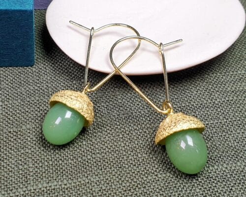 oorsieraden 'Eik'. Gouden eikendopjes met prachtige jade bungelend aan mooie krullen. Vrolijke maatwerk oorbellen uit het Oogst atelier.