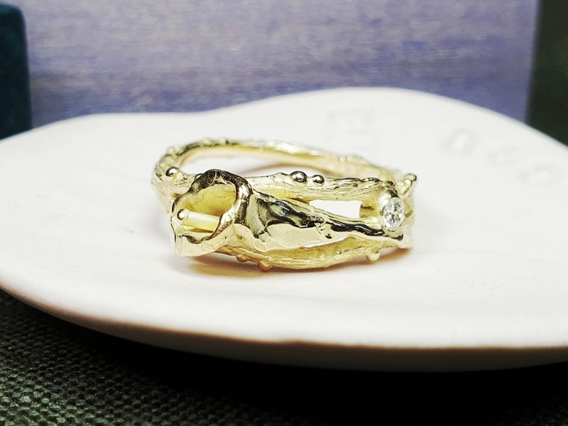 Gedenksieraad. Assieraad. Geelgouden ring Calla Lelie. Takjes met besjes en bloem en een diamant. Maatwerk gedenksieraad. Ontwerp van Oogst Goudsmeden in Amsterdam.