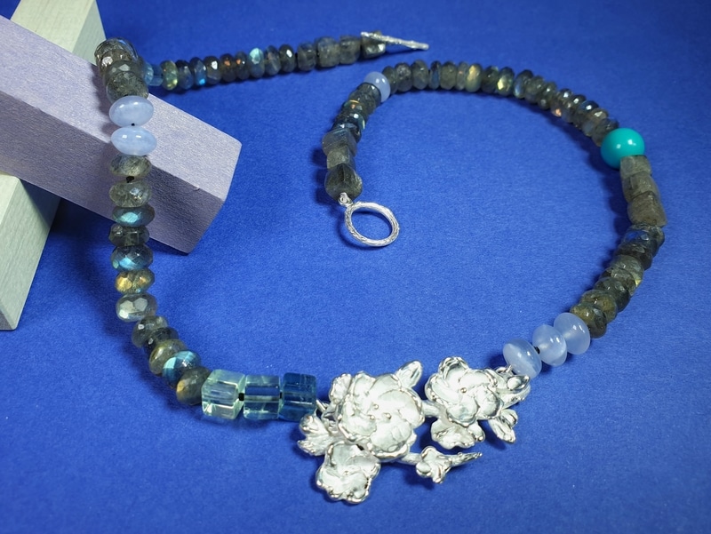 Zilveren collier van bloesemtakje met labradoriet aquamarijn chalcedoon turkoois & fluoriet. Uit de Japonais serie van Oogst Goudsmeden in Amsterdam.