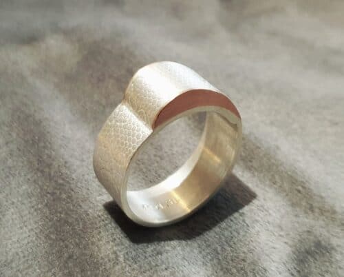 Assieraad, zilveren ring met textuur en roodgouden golf. Maatwerk uit het Oogst atelier.