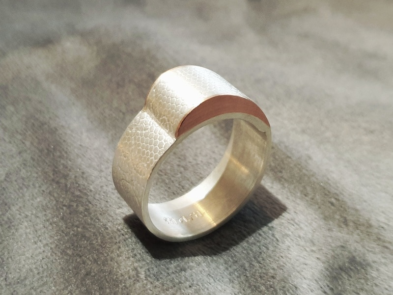 Assieraad, zilveren ring met textuur en roodgouden golf. Maatwerk uit het Oogst atelier.