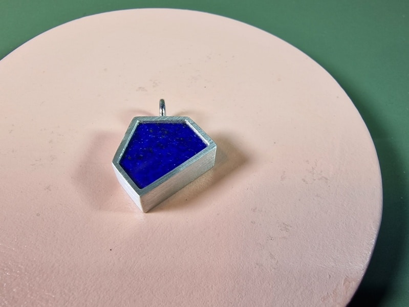 Commemorative jewel. Silver pendant 'House' with Lapis Lazuli, with some cremains underneath the stone. Custom created in the Oogst studio in Amsterdam.