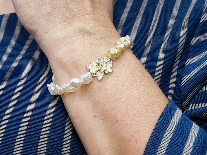 Zuidzee parels armband met geelgouden bloesem motief uit de Japonais serie. exclusief ontwerp van Oogst Sieraden in Amsterdam. Om de pols