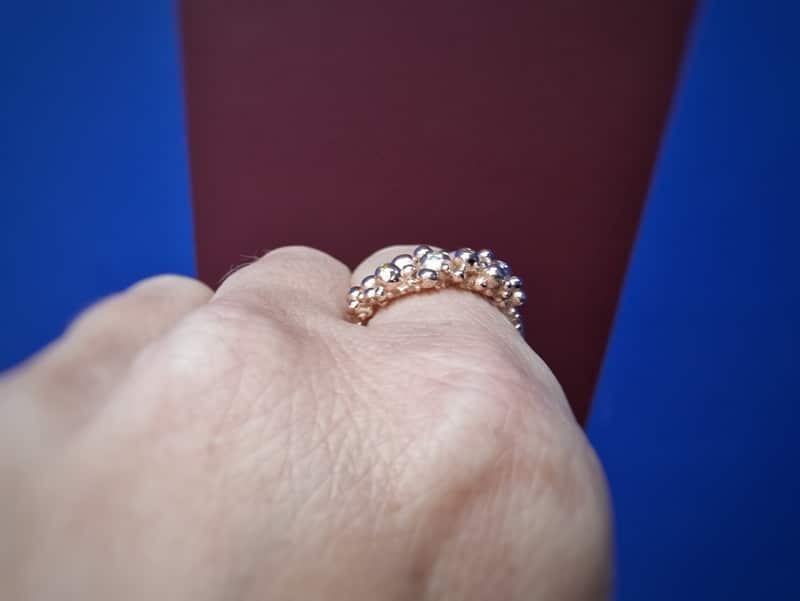 Roodgouden ring bessen en diamant. Takje met speelse besjes en zachte kleur twinkelende diamanten. Oogst ontwerp. Om de vinger, van de zijkant gezien.