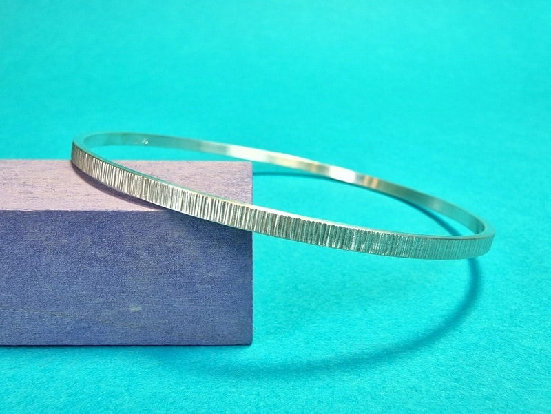 Zilveren armband met structuur van spitse hamering. Rinkelband uit het Oogst atelier in Amsterdam