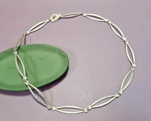 Zilveren ketting Lineair met stofpatroon op de schakels. Ontwerp uit het Oogst goudsmid atelier in Amsterdam.