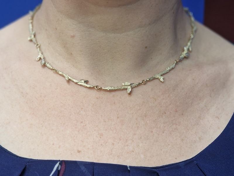 Geelgouden takjes collier om de hals. Sieraadontwerp van Oogst in Amsterdam