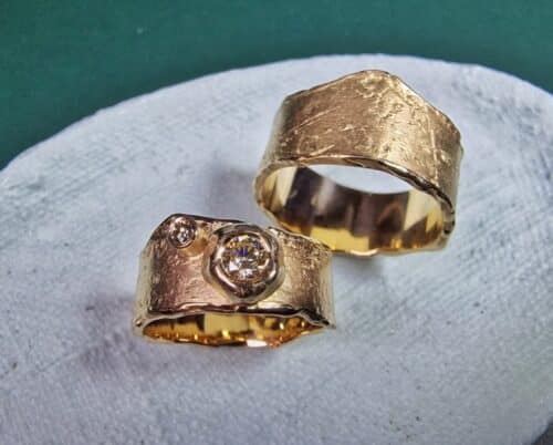 Trouwringen roségoud met structuur uit de Erosie serie. Met een 0,25 ct en een 0,005 ct briljant geslepen diamant. Maatwerk trouwringen set van Oogst Sieraden in Amsterdam.