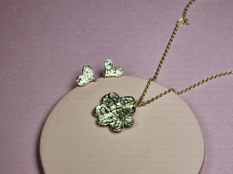 Assieraden hartvormige blaadjes. Geelgouden oorbellen en hanger waar wat as in bewaard wordt. Maatwerk van Oogst Sieraden.