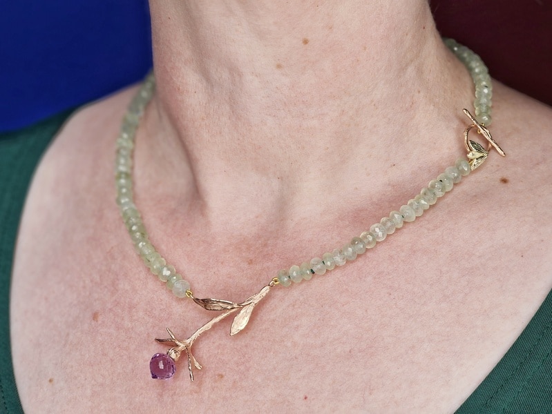 Edelsteen collier prehniet met roodgouden distel met amethist briolet. Collier om de hals. Ontwerp van Oogst Sieraden in Amsterdam.