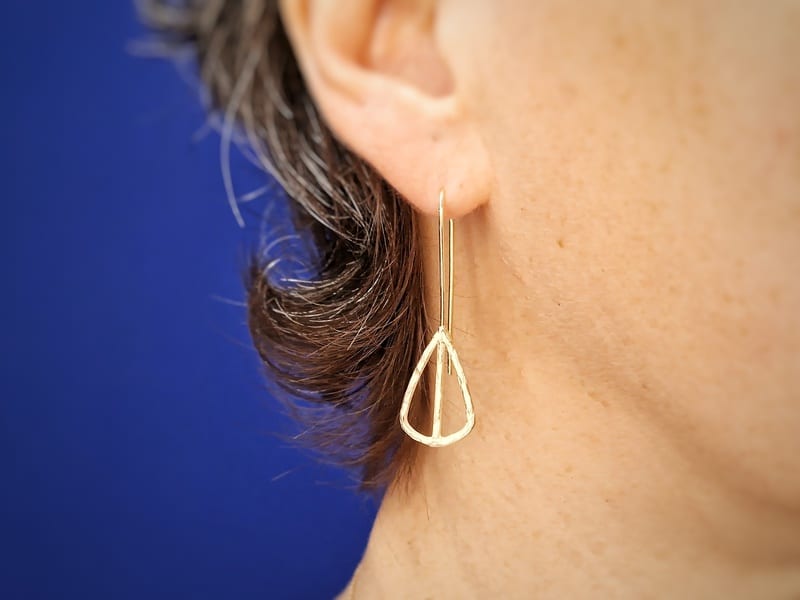 Geelgouden oorsieraden, opengewerkte Mackintosh ornamenten, asymmetrisch paar. Lange oorbellen in het oor, ontwerp van Oogst Goudsmeden in Amsterdam