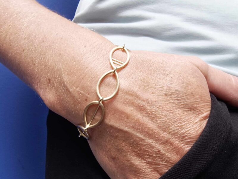 Geelgouden schakel armband opengewerkte Mackintosh ornamenten. Ontwerp van Oogst Goudsmeden in Amsterdam. Om de pols.