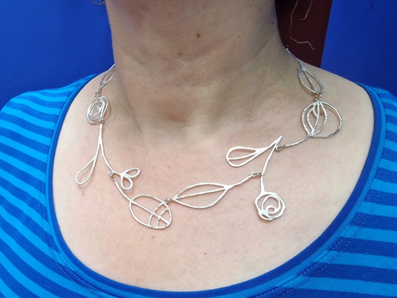 Uit de Schotland serie. Zilveren collier Mackintosh ornamenten. Speels groot collier uit het Oogst atelier. Om de hals gedragen.