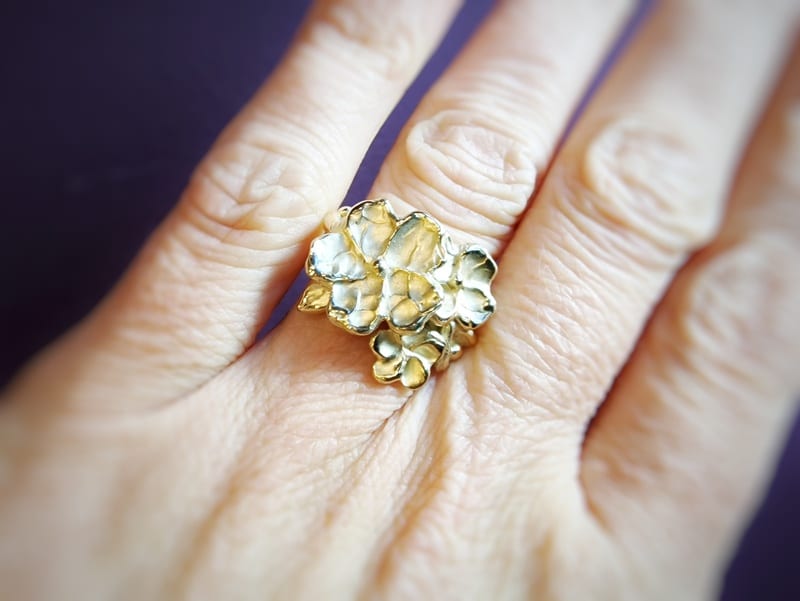 Japonais ring. Geelgouden statement ring met bloesems, bloemknoppen en blaadje. Uitgesproken ontwerp uit het Oogst atelier. Ring om vinger.