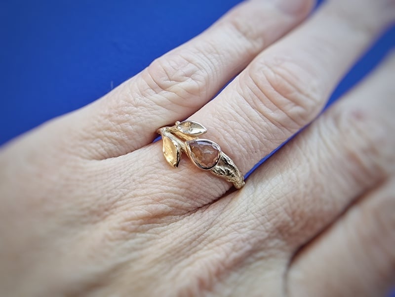 Boomgaard ring roségouden takjes met blaadjes en roestbruine diamant. Oogst ontwerp. Ring om vinger.