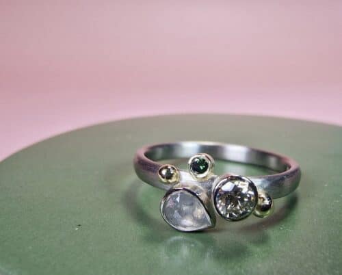 Verlovingsring Verzameling met drie diamanten in witgoud. Een grijze natural diamant peervorm, een cape briljant geslepen diamant en een groene diamantje. Met geelgouden besjes. Oogst Sieraden in Amsterdam. Maatwerk verlovingsring uit eigen atelier.