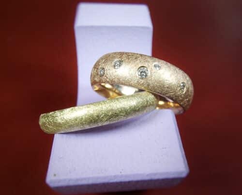 Trouwringen 'Eenvoud'. Roodgouden ring met 5 diamanten speels verdeeld. Geelgouden ring. Kratsmat afgewerkt. Oogst goudsmeden in Amsterdam.