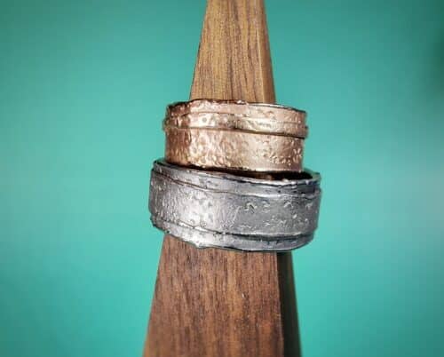 Trouwringen 'Erosie'. Roodgouden brede structuur ring met smalle laag. Witgouden brede structuur ring met brede laag. Wedding rings 'Erosion'. Rose golden texture ring with a small layered band. White gold texture ring with an extra layer. Oogst goldsmith studio in Amsterdam. Standout wedding rings