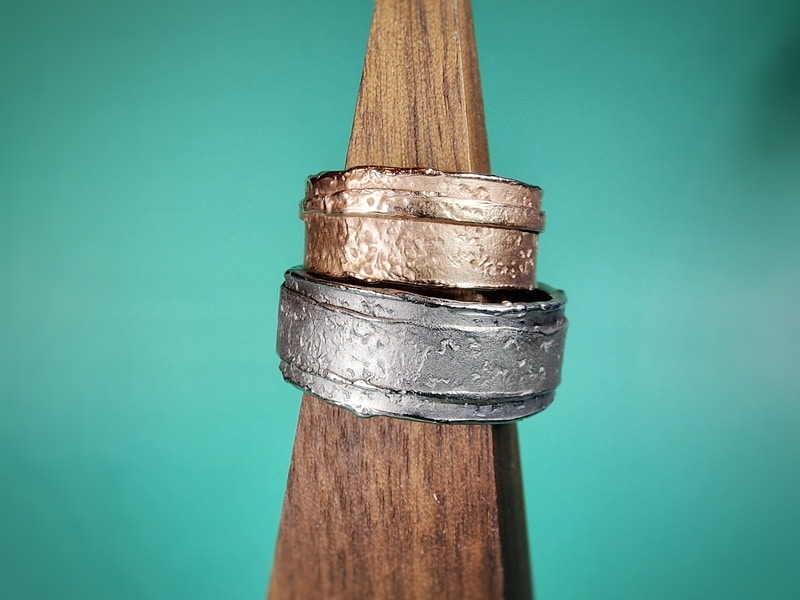 Trouwringen 'Erosie'. Roodgouden brede structuur ring met smalle laag. Witgouden brede structuur ring met brede laag. Wedding rings 'Erosion'. Rose golden texture ring with a small layered band. White gold texture ring with an extra layer. Oogst goldsmith studio in Amsterdam. Standout wedding rings