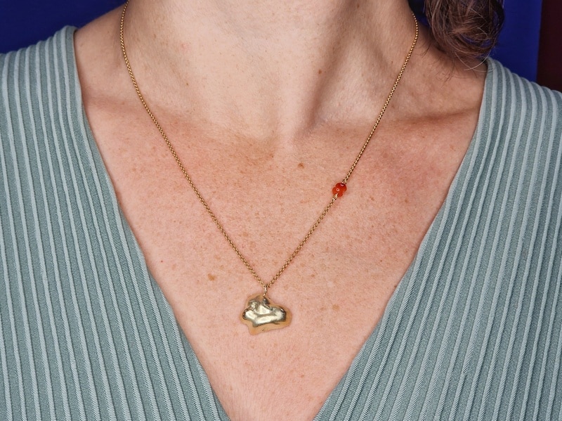 Gouden collier met hanger Wolk en een accent van carneool. Gezien om de hals. Speels ontwerp van Oogst Goudsmeden.