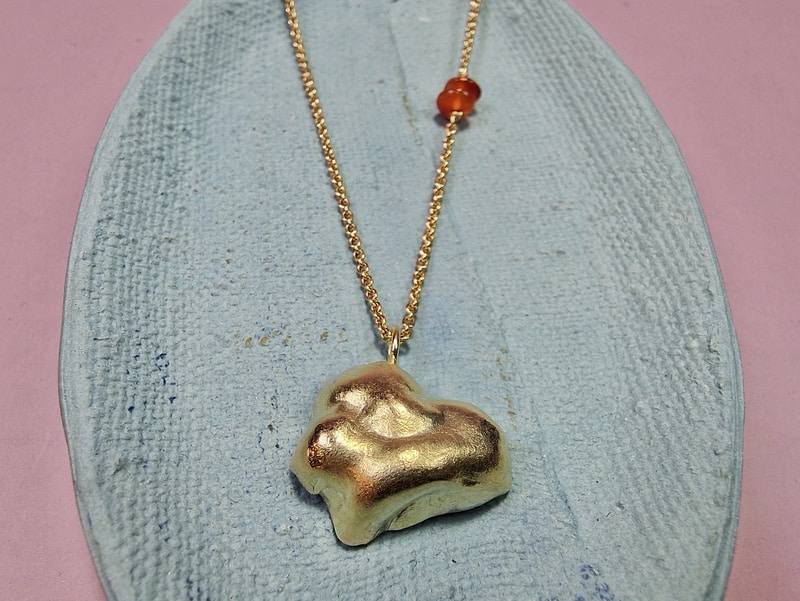 Gouden collier met hanger Wolk en een accent van carneool. Speels ontwerp van Oogst Goudsmeden.