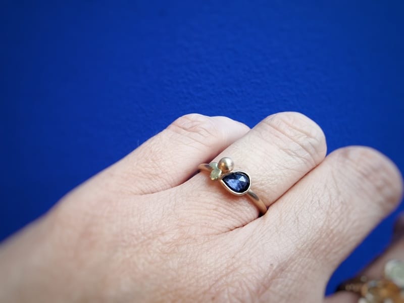 Roségouden Besjes ring met peervormige saffier en geelgouden blaadjes. Om de vinger.