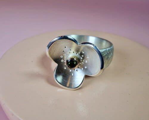 Statement ring 'In bloei'. Kloeke zilveren ring met bloem en 0,09 crt briljant geslepen groene toermalijn in roodgoud gezet. Blikvanger van Oogst.