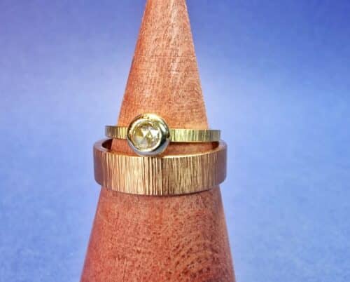 Trouwringen met spitse hamerslag. Geelgouden damesring met een roosgeslepen diamant. Roodgouden herenring. Uit het Oogst atelier.
