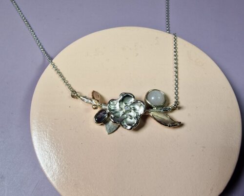 Witgouden collier met bloesem, blaadjes en geboortestenen. Roze maansteen en Alexandriet. Geboortesieraad van Oogst. Maatwerk uit het Oogst atelier in Amsterdam.
