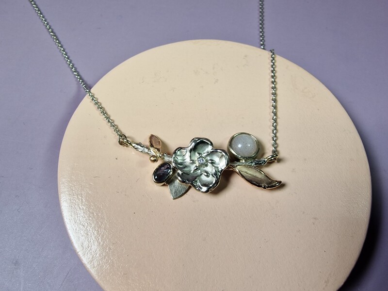 Birth jewel. White gold necklace with moonstone, diamond and alexandrite. With playful blossom and rose gold leaves. Created by Oogst.