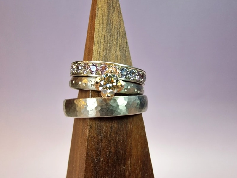 White gold wedding ring 'Rhythm' with hammering. Engagement ring with a 0,36 ct diamond light brown with fine hammering and playful dots. Stack ring white gold eternity ring pavé set all around spinel. Modern classics created in the Oogst studio.
