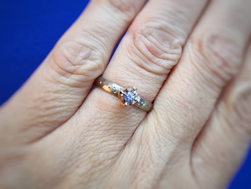 Witgouden verlovingsring 'Ritme' met 0,36 crt diamant light brown en fijne hamerslag en speelse stipjes. Uit het Oogst atelier. Gezien om de vinger.