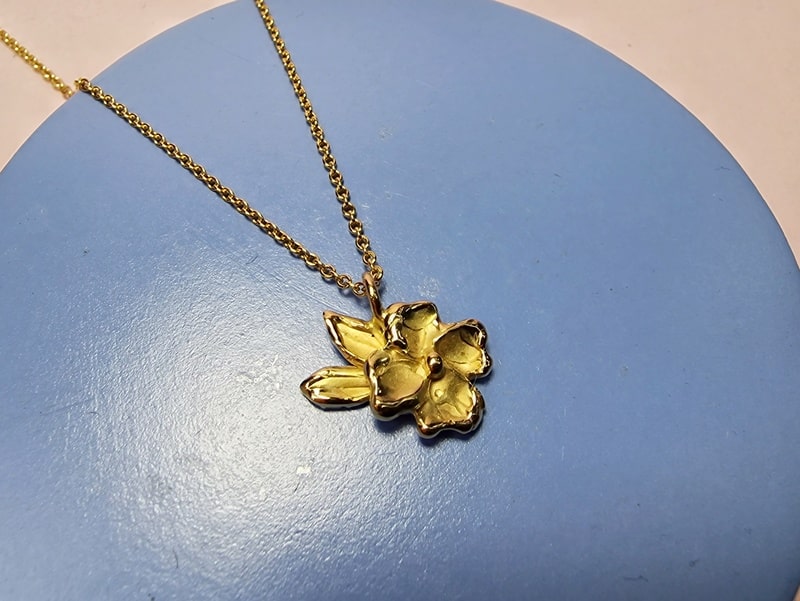 Japonais geelgouden bloesem en blaadjes hanger aan een kettinkje. Ontwerp uit het Oogst atelier.