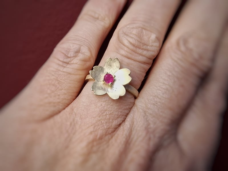 Edelsteen ring met geelgouden Sakura, de kersenbloesem, met verfijnde handgravure. Met Robijn, de geboortesteen van juli. Bijzonder stuk van Oogst. Gezien om de vinger.