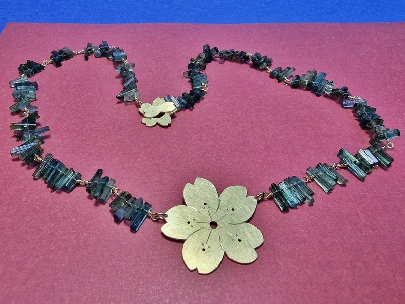 Collier Sakura. De geelgouden kersenbloesem met petrol toermalijn kristallen gecombineerd komt uit de japonais serie van Oogst in Amsterdam.