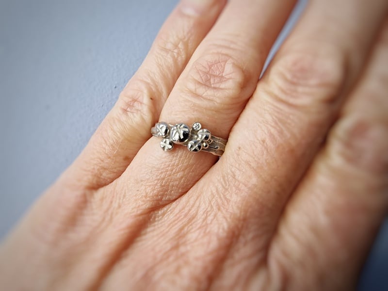 Ring witgoud Erosie en Bessen met diamant om vinger gedragen. Ring witgoud Erosie en Bessen met diamant om vinger gedragen. Speels ontwerp van Oogst Goudsmeden.