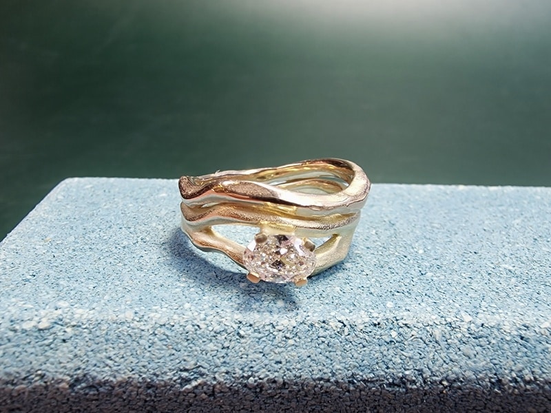 Yellow gold diamond ring Wave with a 0,55 oval cut diamond champagne. Next to a Wave wedding ring. Created at the Oogst studio.