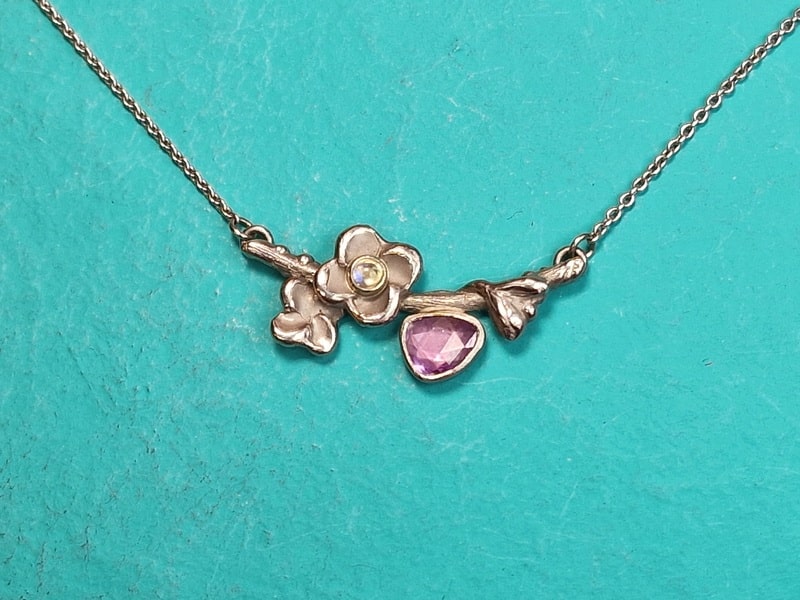 Birth jewel. White gold necklace with moonstone and purple sapphire. With playful blossom and leaves. Birth jewel created by Oogst.