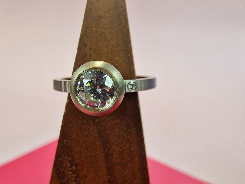 Ring 'Boletus'. White gold slim ring with pointy hammering and a brilliant cut heirloom diamond in a rounded setting and another own diamond set into the band. Custom created at the Oogst studio