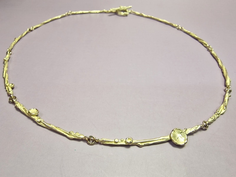 Yellow gold refined necklace from the 'Twist' series with subtile berries, fungus and peaches details. With a toggle clasp. Elegant Oogst Original.