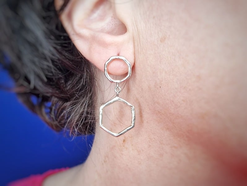 Zilveren oorsieraden amorfe vormen onder elkaar, in het oor. Uit het Oogst atelier.