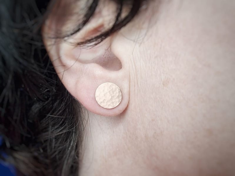 Roodgouden oorsieraden, grafische cirkels met hamerslag, in het oor, de grote cirkel. Uit het Oogst atelier.