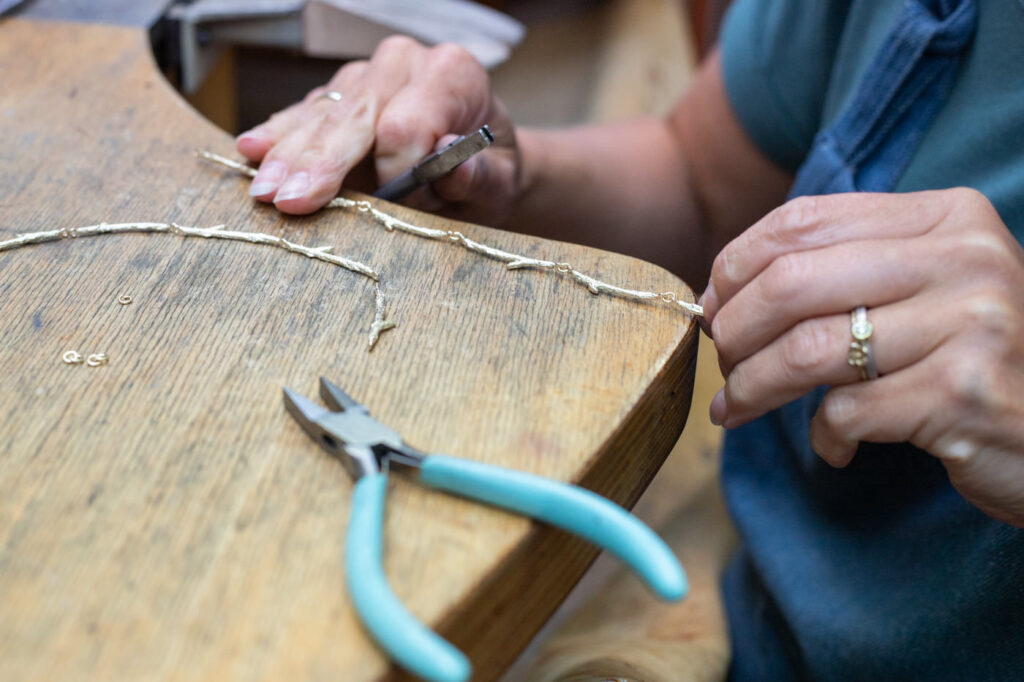 In elkaar monteren van een gouden collier. In het goudsmid atelier van Oogst