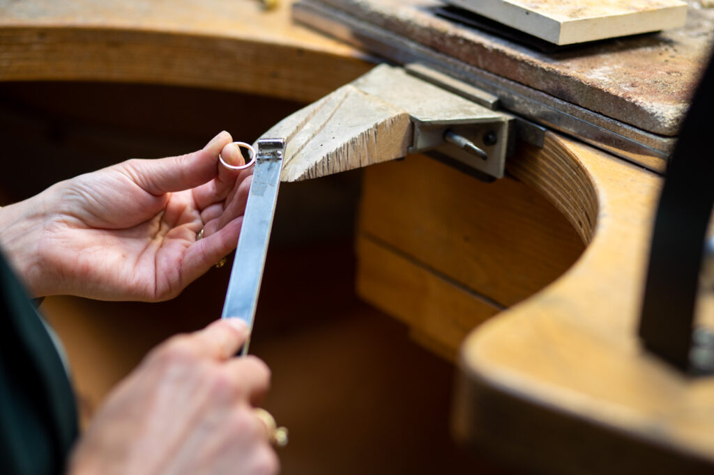 Schuren van een sieraad in het Oogst goudsmid atelier. Aan de werkbank.