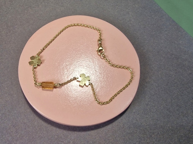 Yellow gold 'In bloom' bracelet with Marigold flowers, the birth month flower for October, and a twinkling Imperial Topaz. Unique refined bracelet by Oogst.